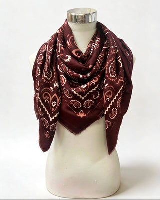 A dark burgundy bandana scarf with a cream paisley pattern, draped on a white mannequin torso against a white background.