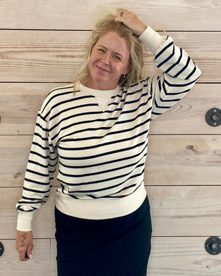Person wearing a black and white striped sweater against a wooden wall.