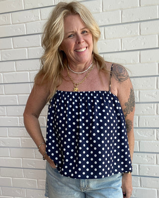 Women's navy and white polka dot tank top with spaghetti straps, an open neckline, and a relaxed fit.
