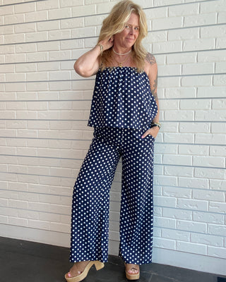 Women's navy and white polka dot wide-leg trousers with a smocked waistband, pull-on fit, front pockets, and a relaxed drapey silhouette with top