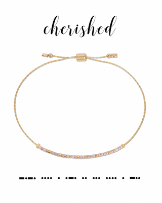 Gold bracelet with clear stones on a white background, featuring the word 'cherished' in morse code.