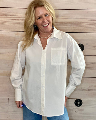 Woman wearing a white blouse over a blue shirt against a wooden background