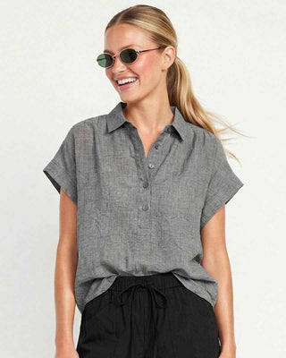 Woman wearing a gray short-sleeve shirt and black shorts on a white background