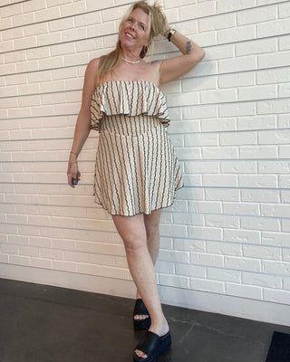Woman in a striped dress standing against a white brick wall