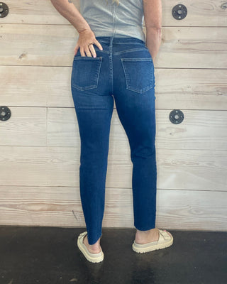 Person wearing blue jeans and a gray shirt lying on a wooden floor.