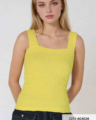 Woman wearing a yellow tank top against a white background