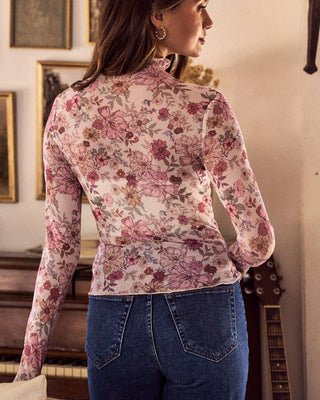 Woman wearing a floral blouse and jeans in an indoor setting