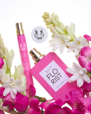 Pink perfume bottle with 'Flo Rist' branding surrounded by flowers on a white background