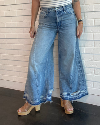 Person wearing blue jeans and a striped top on a white tiled floor.