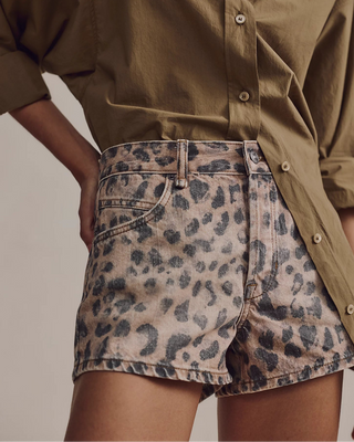 Person wearing a green shirt and leopard print skirt on a neutral background