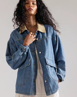 Woman wearing a denim jacket with a plain background