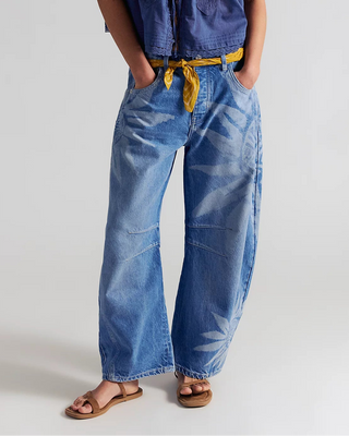 Woman wearing a blue denim outfit with wide-leg jeans and a matching top on a white background