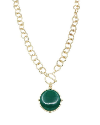 A gold chain necklace featuring a round green stone pendant in a gold bezel setting, suspended from a curb link chain with a toggle clasp, shown on a plain white background.