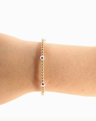 Gold bracelet on a person's wrist against a white background