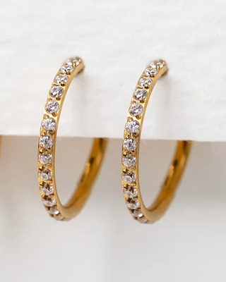 Set of gold hoop earrings with embedded stones on a white surface