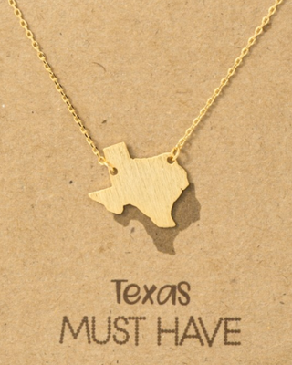 Gold necklace with Texas-shaped pendant on a brown card with 'Texas MUST HAVE' text.