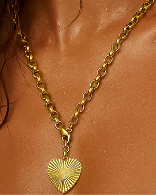 Gold necklace with a heart pendant on a person's neck