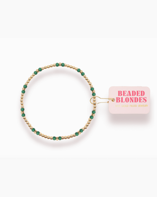 Gold and green beaded bracelet with 'Beaded Blondes' packaging on a white background