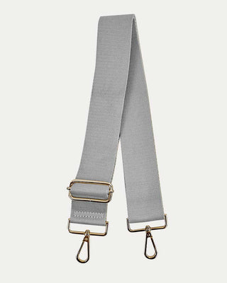 Gray bag strap with gold hardware on a light gray background