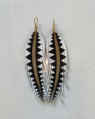 Pair of feather-shaped earrings with black and white pattern on a light gray background