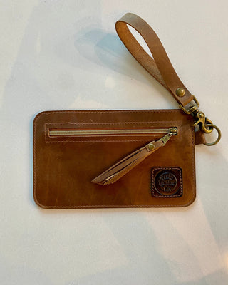 Brown leather wristlet with a zipper on a white background