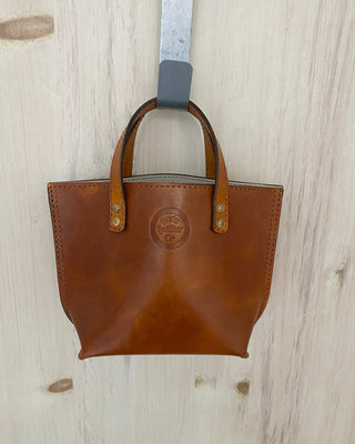 Brown leather handbag with a visible brand logo on a light wooden surface