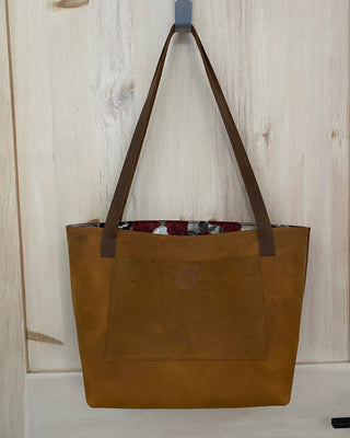 Brown leather tote bag on a light wooden floor
