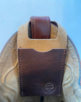 Brown leather boot wallet attached to a cowboy boot with a blue background