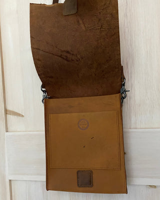 Brown leather bag with a visible brand logo on a light wooden surface