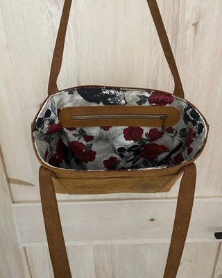 Floral-patterned bag with a wooden frame on a light wood floor.