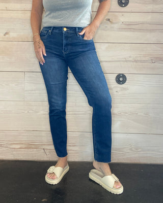 Person wearing blue jeans and a light gray top on a wooden floor.
