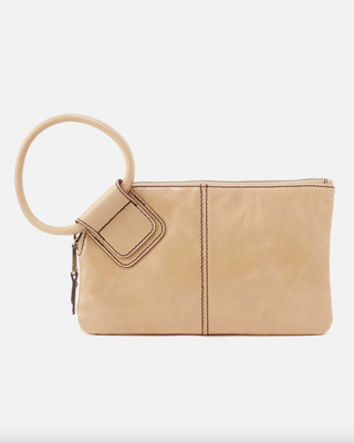 Beige clutch bag with a circular handle on a white background