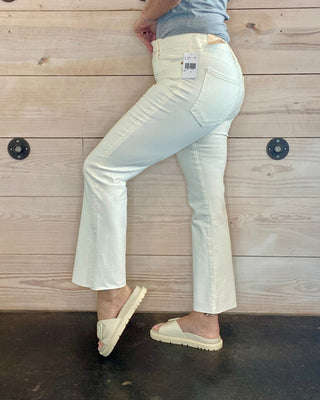 Person wearing light-colored pants and espadrilles against a wooden wall.