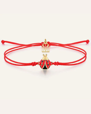 A red adjustable cord bracelet featuring a gold-tone crown charm and a red and black ladybug charm with small blue accents, displayed on a clean off-white background.
