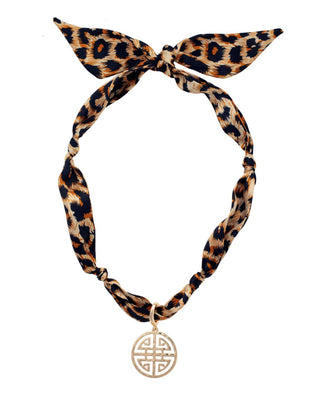 Leopard print scarf necklace with a gold pendant on a white background