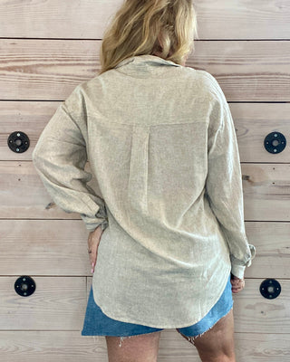 Person wearing a beige shirt and denim shorts against a wooden background