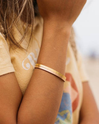 Gold bracelet on a wrist with a blurred background