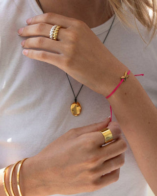 Close-up of hands wearing gold rings and bracelets on a white background