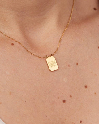 Gold necklace with a pendant on a person's neck