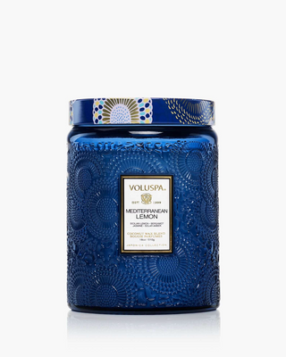 Blue candle with decorative lid featuring Voluspa branding on a white background