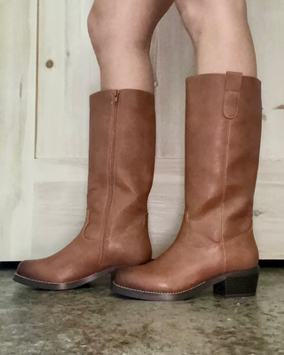 Brown knee-high boots worn indoors on a concrete floor.