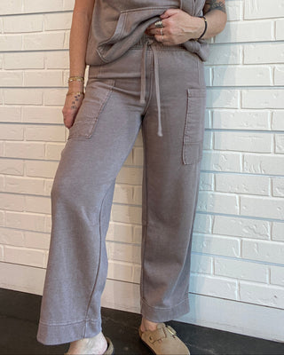 Person wearing a gray outfit against a white brick wall.