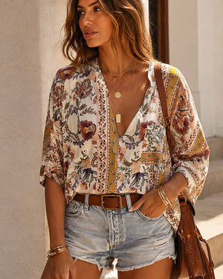 Woman wearing a patterned blouse and denim shorts, standing outdoors.