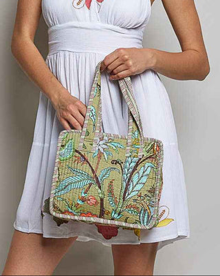 Woman holding a colorful handbag wearing a white dress with floral embroidery.