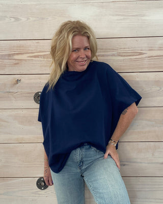 Person wearing a navy sweater and light blue jeans on a wooden floor