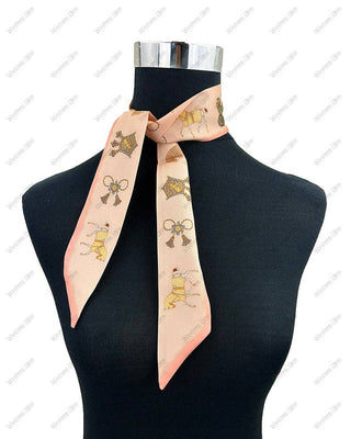 A peach-colored silk scarf with a pattern of cartoon dogs in a carriage and bows, styled on a black mannequin torso against a white background with a faint watermark pattern.