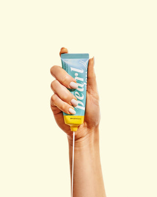 Hand holding a tube of 'Pearl' product against a white background