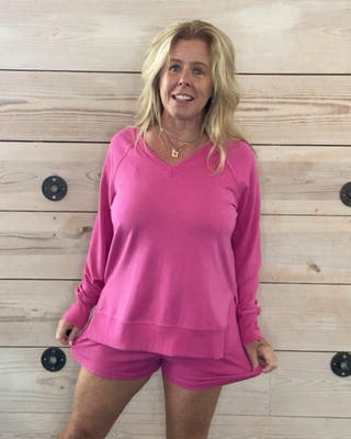 Person wearing a pink outfit standing in front of a wooden wall.