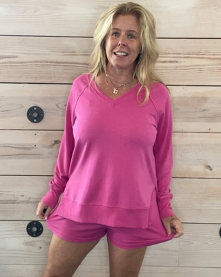 Person wearing a pink outfit standing in front of a wooden wall with a video editing interface overlay.