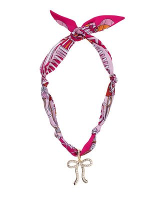 Pink patterned scarf necklace with a decorative bow charm on a white background